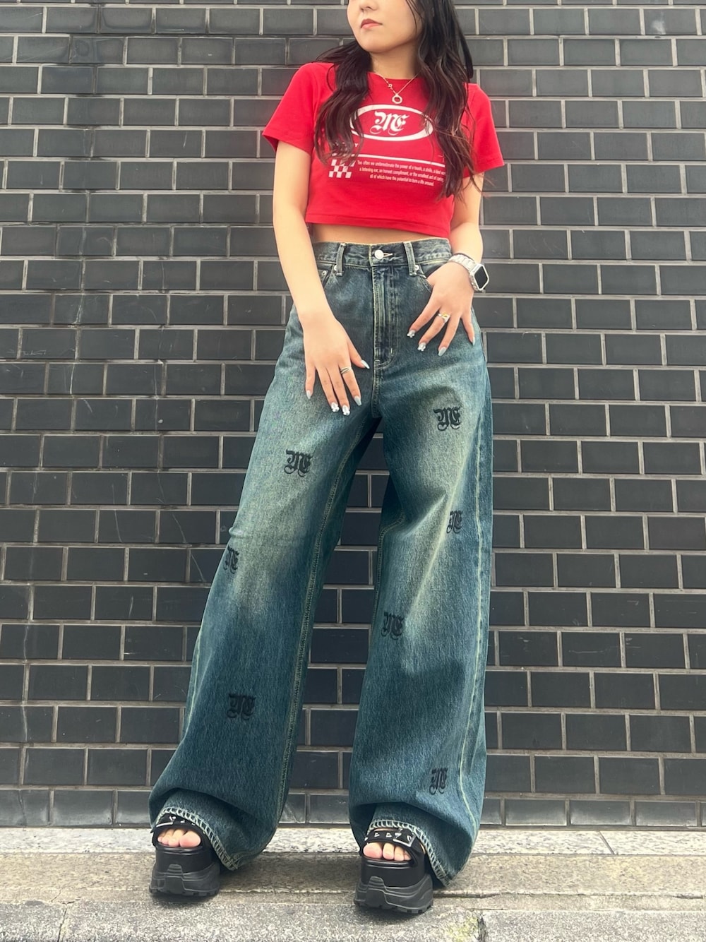 レッド系のTシャツ/カットソー、ブルー系のデニムパンツ、ブラック系のサンダルを着用したレディースの春コーディネートの1枚目の写真