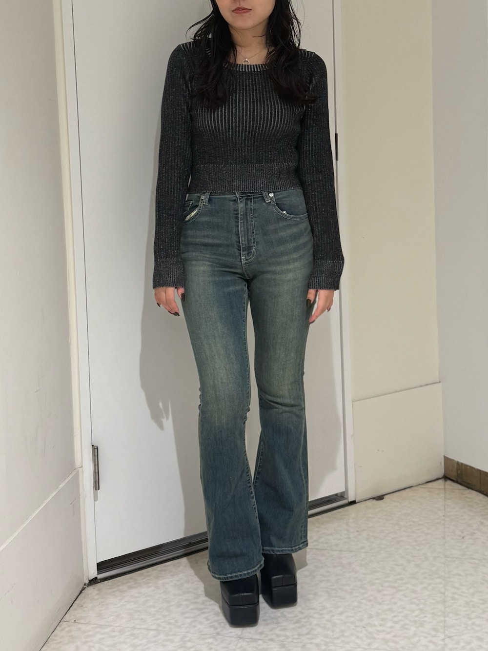ブルー系のデニムパンツ、ブラック系のニット/セーター、ブラック系のブーツを着用したレディースの秋コーディネートの1枚目の写真