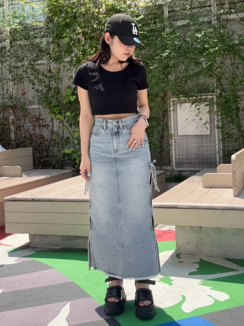 ブラウン系のサンダル、ブルー系のデニムスカート、ブラック系のTシャツ/カットソーを着用したレディースの春コーディネートの1枚目の写真