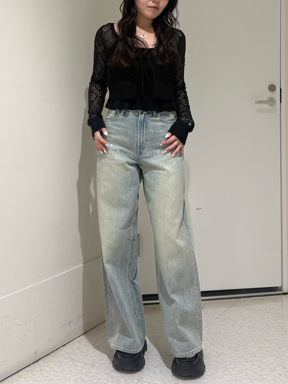 ブラック系のカーディガン/ボレロ、ブルー系のデニムパンツ、ブラック系のサンダルを着用したレディースの春コーディネートの1枚目の写真