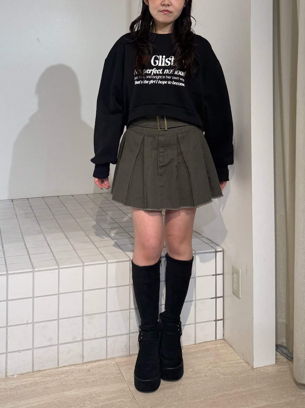 ブラック系のスウェット、ブラック系のブーツ、グレー系のスカートを着用したレディースの秋コーディネートの1枚目の写真