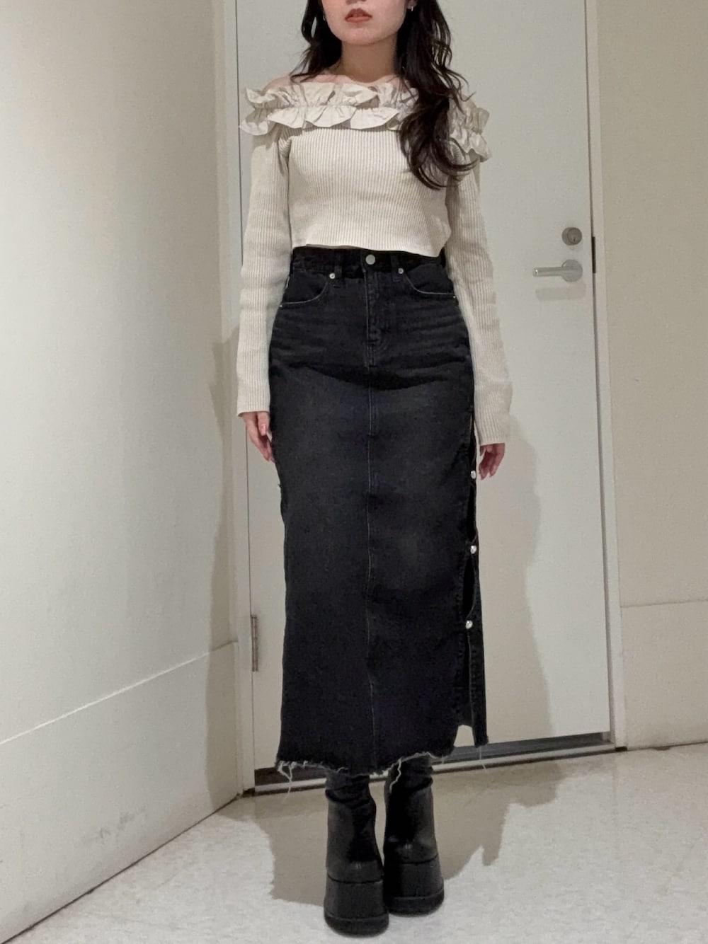 ベージュ系のニット/セーター、ブラック系のデニムスカート、ブラック系のブーツを着用したレディースの春コーディネートの1枚目の写真