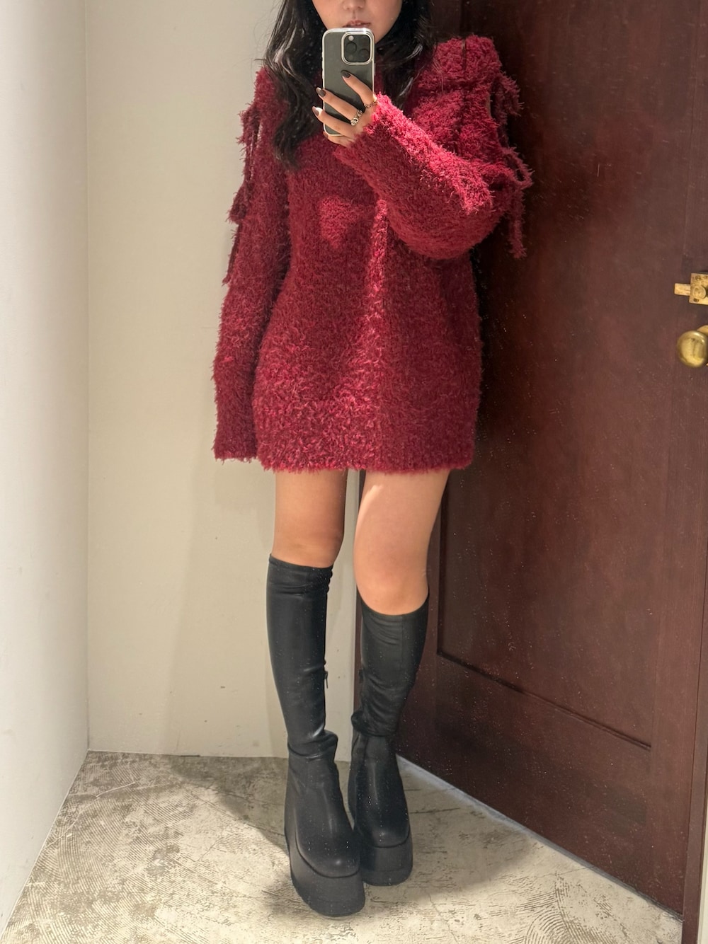 レッド系のワンピース、ブラック系のブーツを着用したレディースの秋コーディネートの1枚目の写真