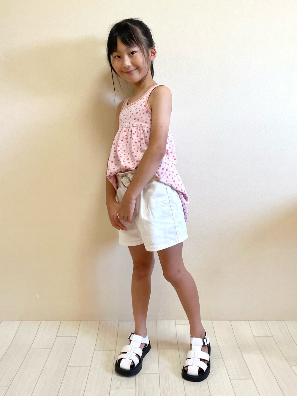 ピンク系のワンピース、ホワイト系のパンツ、ホワイト系のサンダルを着用したキッズの夏コーディネートの1枚目の写真