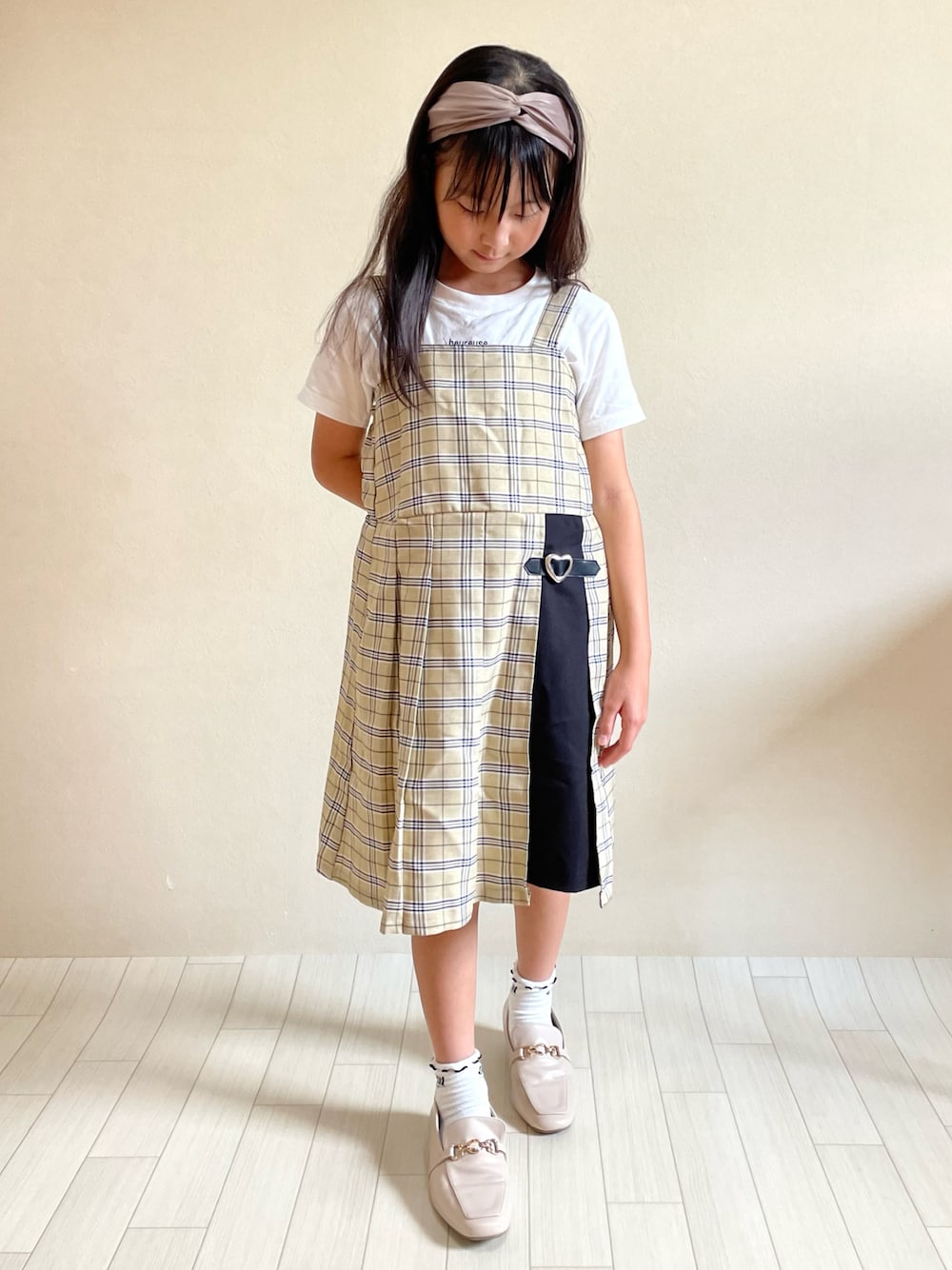 ベージュ系のワンピース、ベージュ系のローファー、ホワイト系のTシャツ/カットソーを着用したキッズの秋コーディネートの1枚目の写真