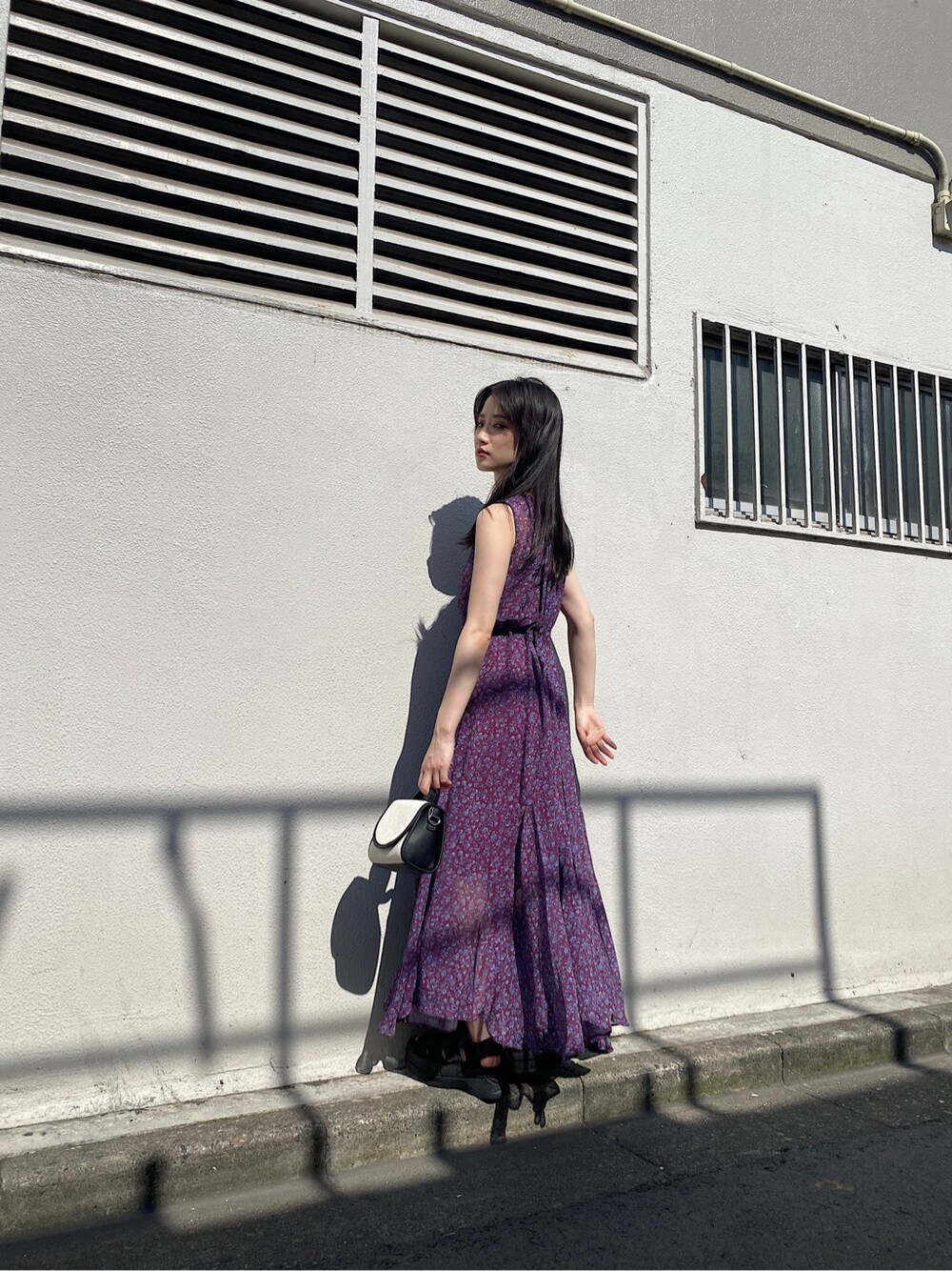 パープル系のワンピース、ブラック系のサンダル、ゴールド系のイヤリングを着用したレディースの夏コーディネートの1枚目の写真