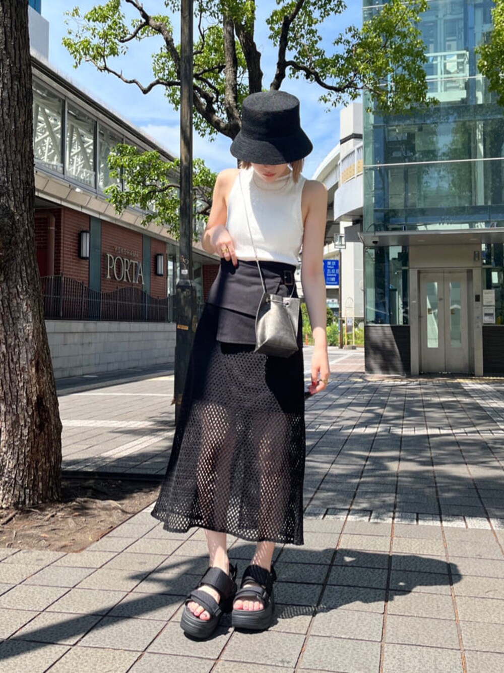 ホワイト系のサンダル、ブラック系のスカート、ホワイト系のタンクトップを着用したレディースの夏コーディネートの1枚目の写真