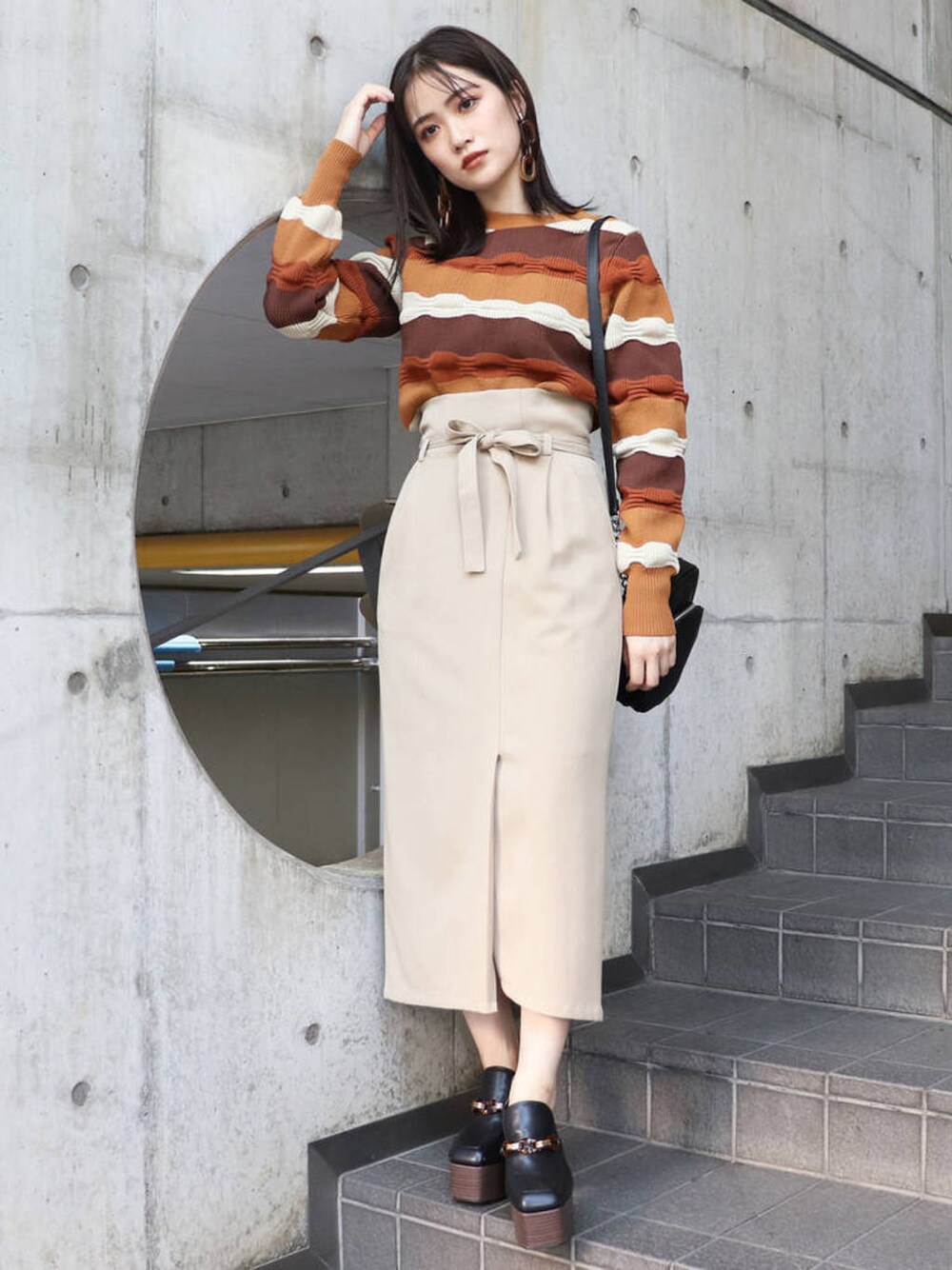 ブラック系のショルダーバッグ、ブラック系のローファー、ブラウン系のニット/セーターを着用したレディースの冬コーディネートの1枚目の写真