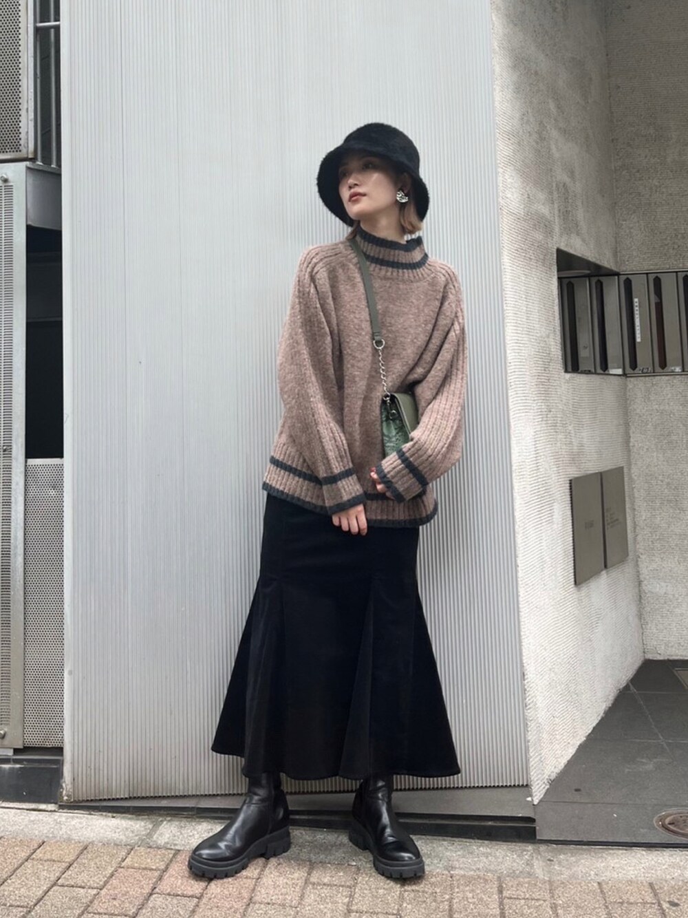 ブラウン系のニット/セーター、グリーン系のショルダーバッグ、ブラック系のスカートを着用したレディースの夏コーディネートの1枚目の写真