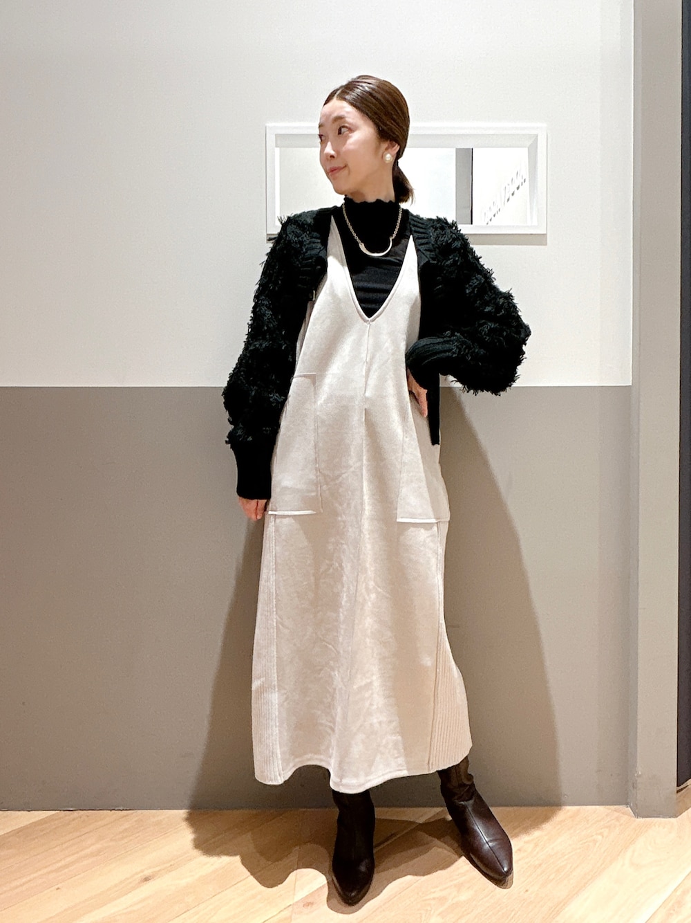 ブラック系のカーディガン/ボレロ、ベージュ系のジャンパースカート、ブラック系のTシャツ/カットソーを着用したレディースの冬コーディネートの1枚目の写真