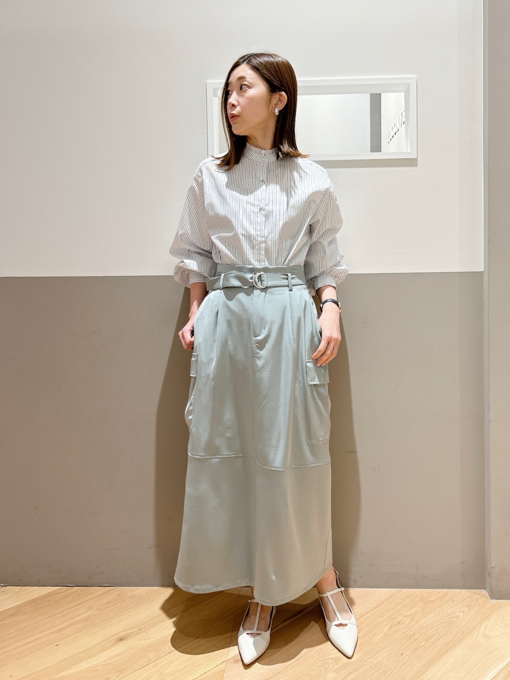 ホワイト系のシャツ/ブラウス、グリーン系のスカート、ホワイト系のパンプスを着用したレディースの春コーディネートの1枚目の写真