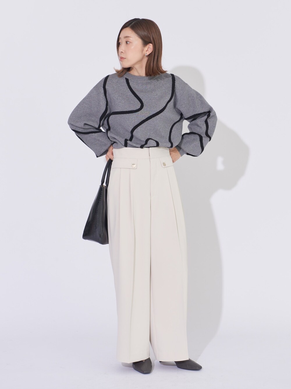 グレー系のニット/セーター、ホワイト系のその他パンツ、ブラック系のトートバッグを着用したレディースの冬コーディネートの1枚目の写真