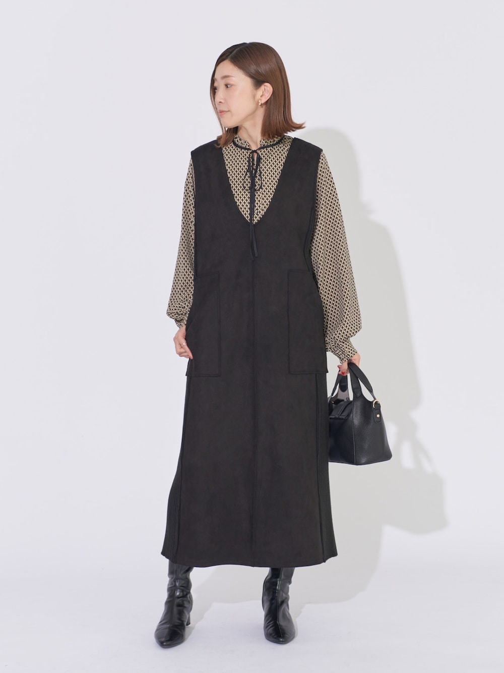 ブラック系のジャンパースカート、ブラック系のシャツ/ブラウス、ブラック系のハンドバッグを着用したレディースの冬コーディネートの1枚目の写真