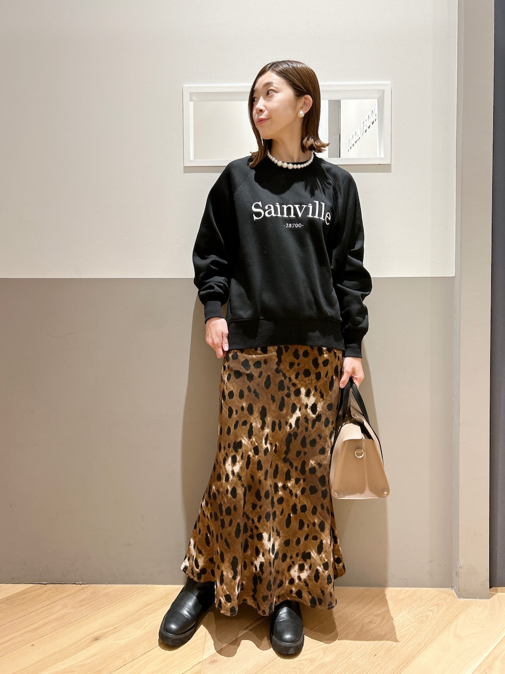 ブラック系のスウェット、ブラウン系のスカート、ブラック系のシューズを着用したレディースの冬コーディネートの1枚目の写真