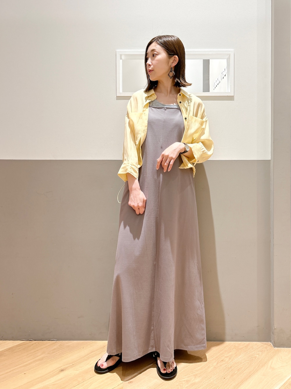 イエロー系のワンピース、グレー系のイヤリングを着用したレディースの春コーディネートの1枚目の写真