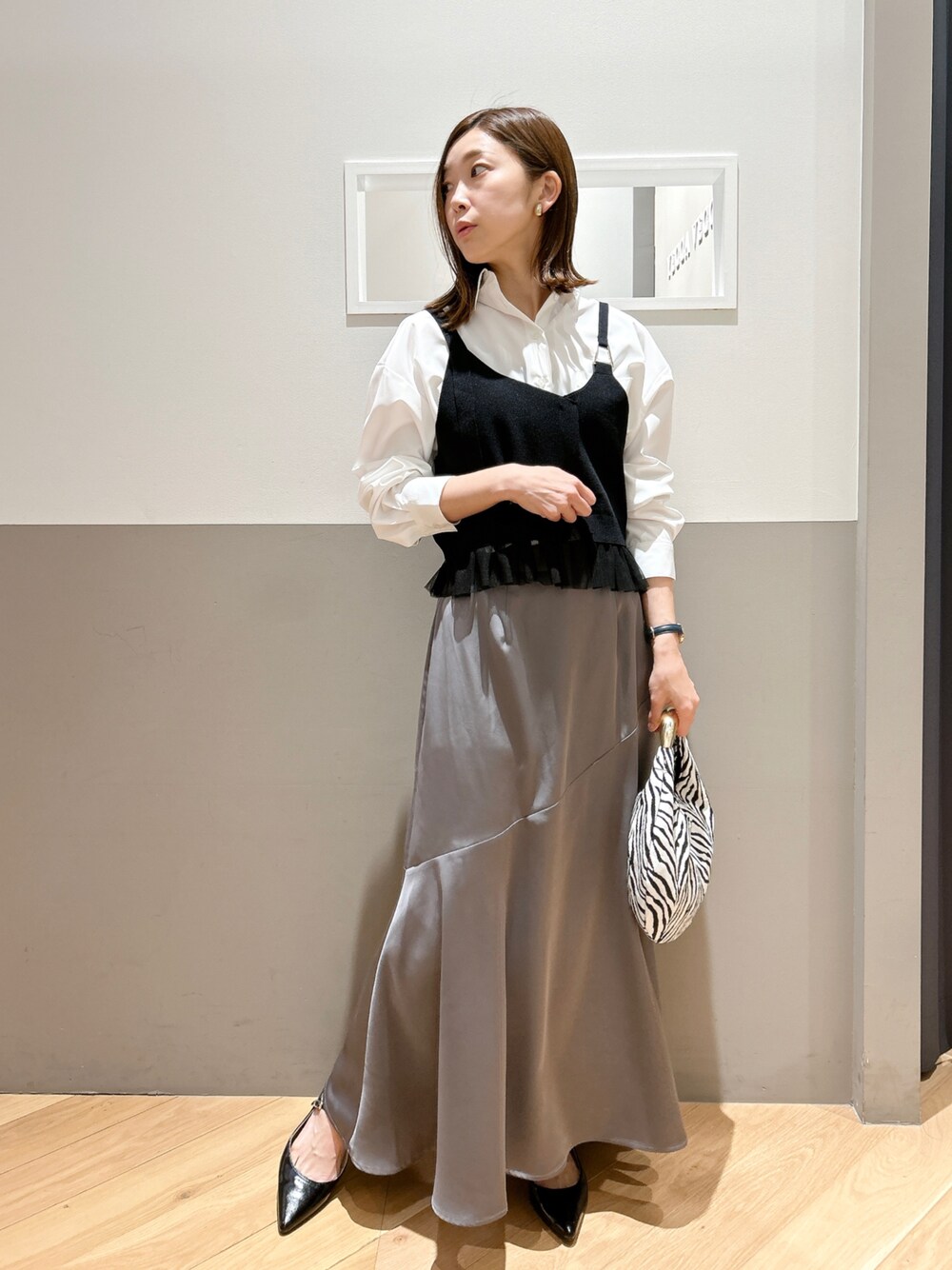 ホワイト系のTシャツ/カットソー、グレー系のスカート、ブラック系のパンプスを着用したレディースの冬コーディネートの1枚目の写真