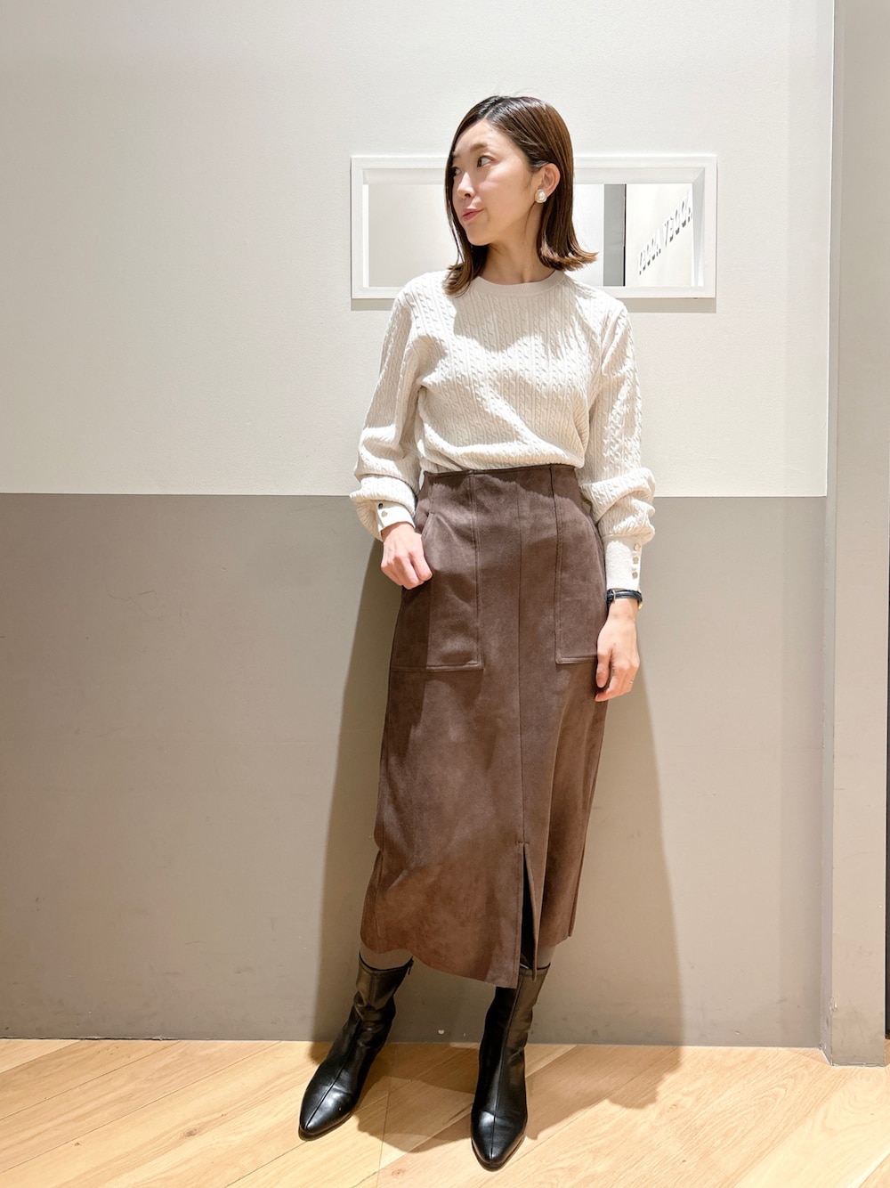 ホワイト系のニット/セーター、ブラウン系のスカート、ブラック系のシューズを着用したレディースの冬コーディネートの1枚目の写真