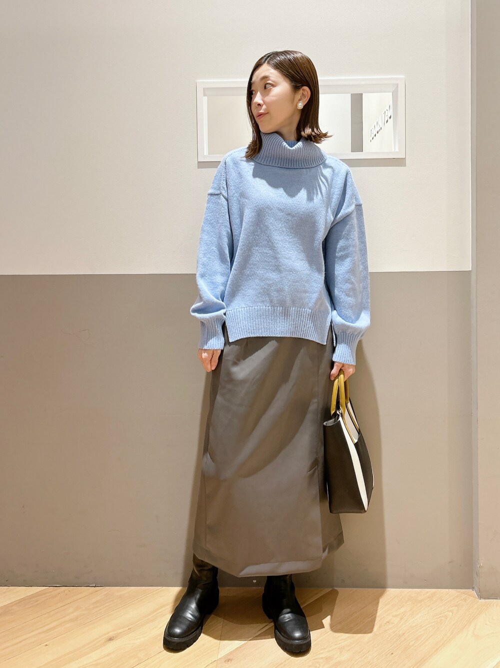 ブルー系のニット/セーター、グレー系のスカート、ブラック系のシューズを着用したレディースの冬コーディネートの1枚目の写真