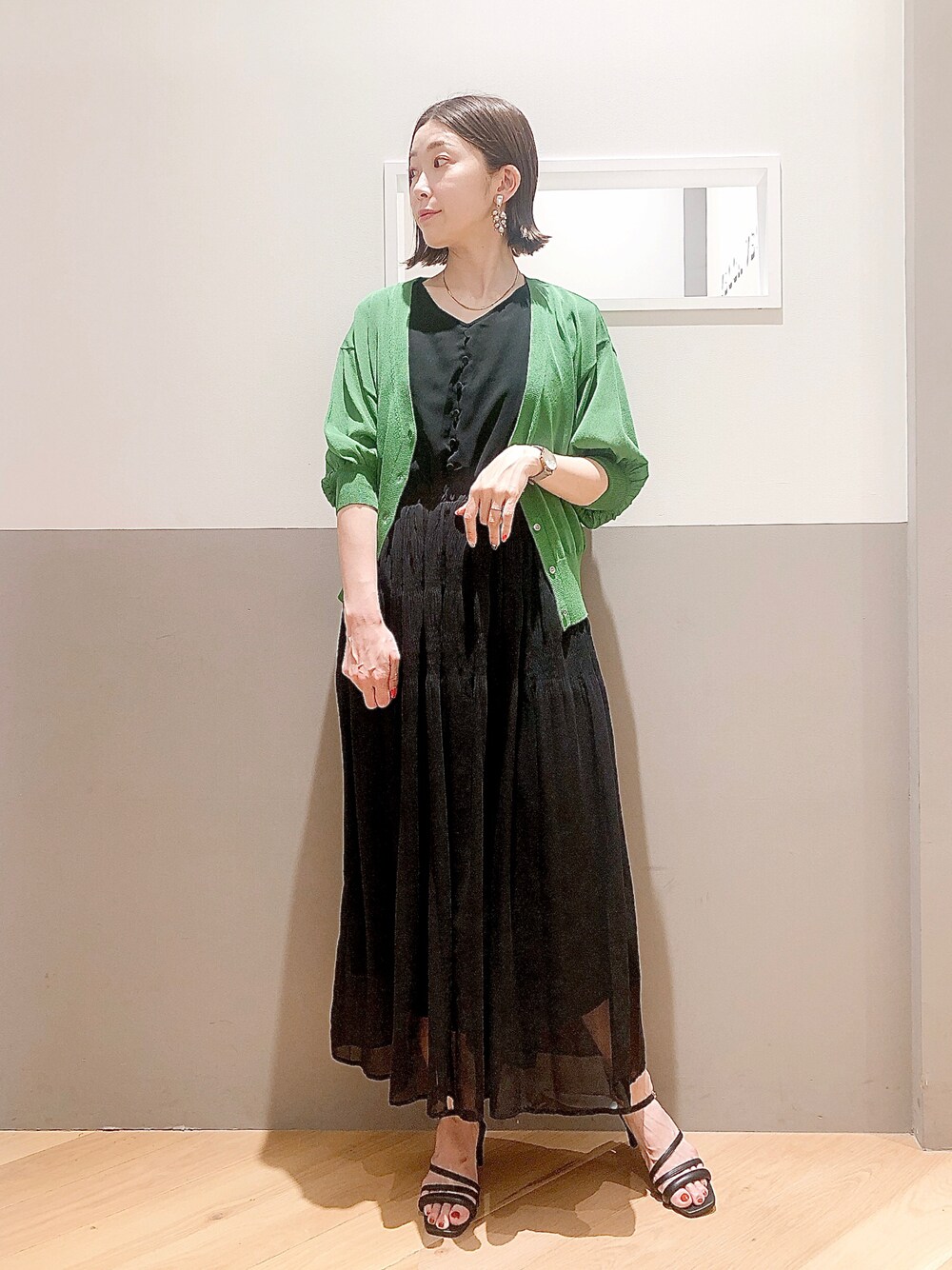 ブラック系のワンピース、グリーン系のカーディガン/ボレロ、ブラック系のサンダルを着用したレディースの夏コーディネートの1枚目の写真