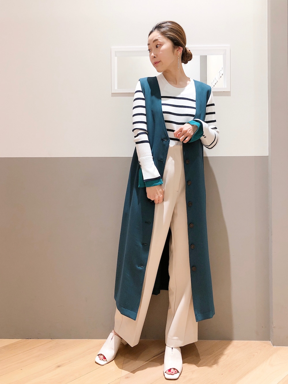 ブルー系のジャンパースカート、その他のニット/セーター、ベージュ系のパンツを着用したレディースの春コーディネートの1枚目の写真