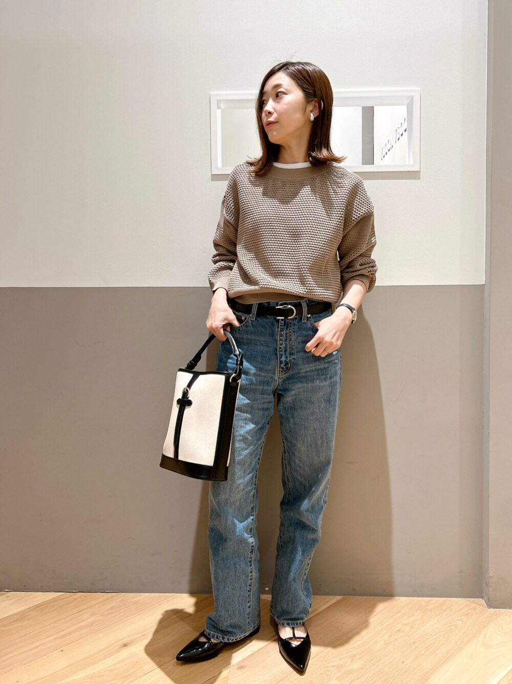 ベージュ系のニット/セーター、ホワイト系のTシャツ/カットソー、ブルー系のデニムパンツを着用したレディースの春コーディネートの1枚目の写真