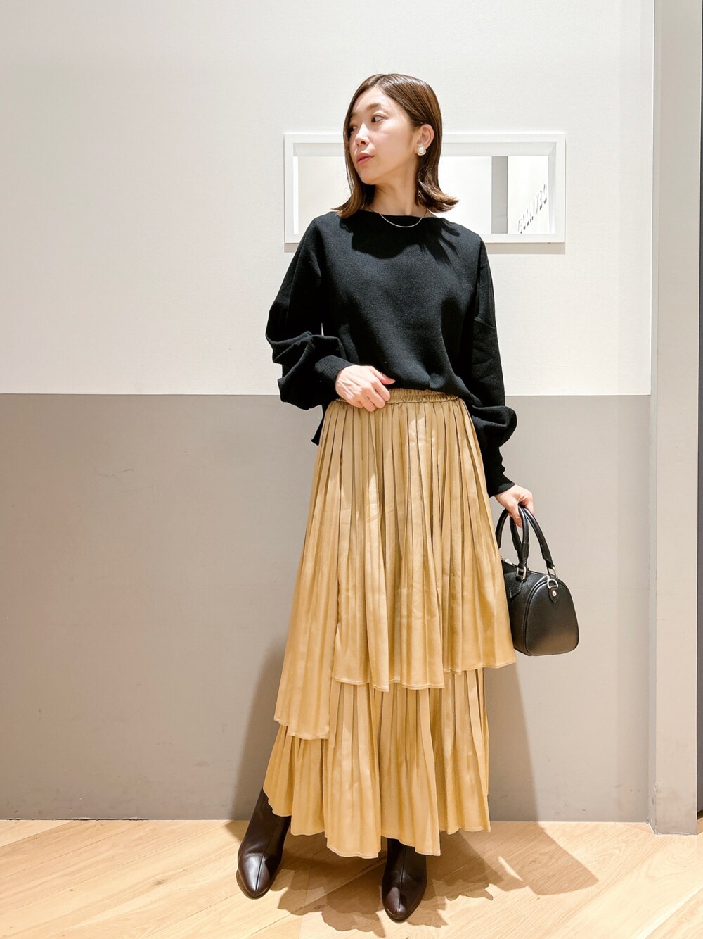 ブラック系のニット/セーター、ゴールド系のスカート、ブラウン系のシューズを着用したレディースの秋コーディネートの1枚目の写真