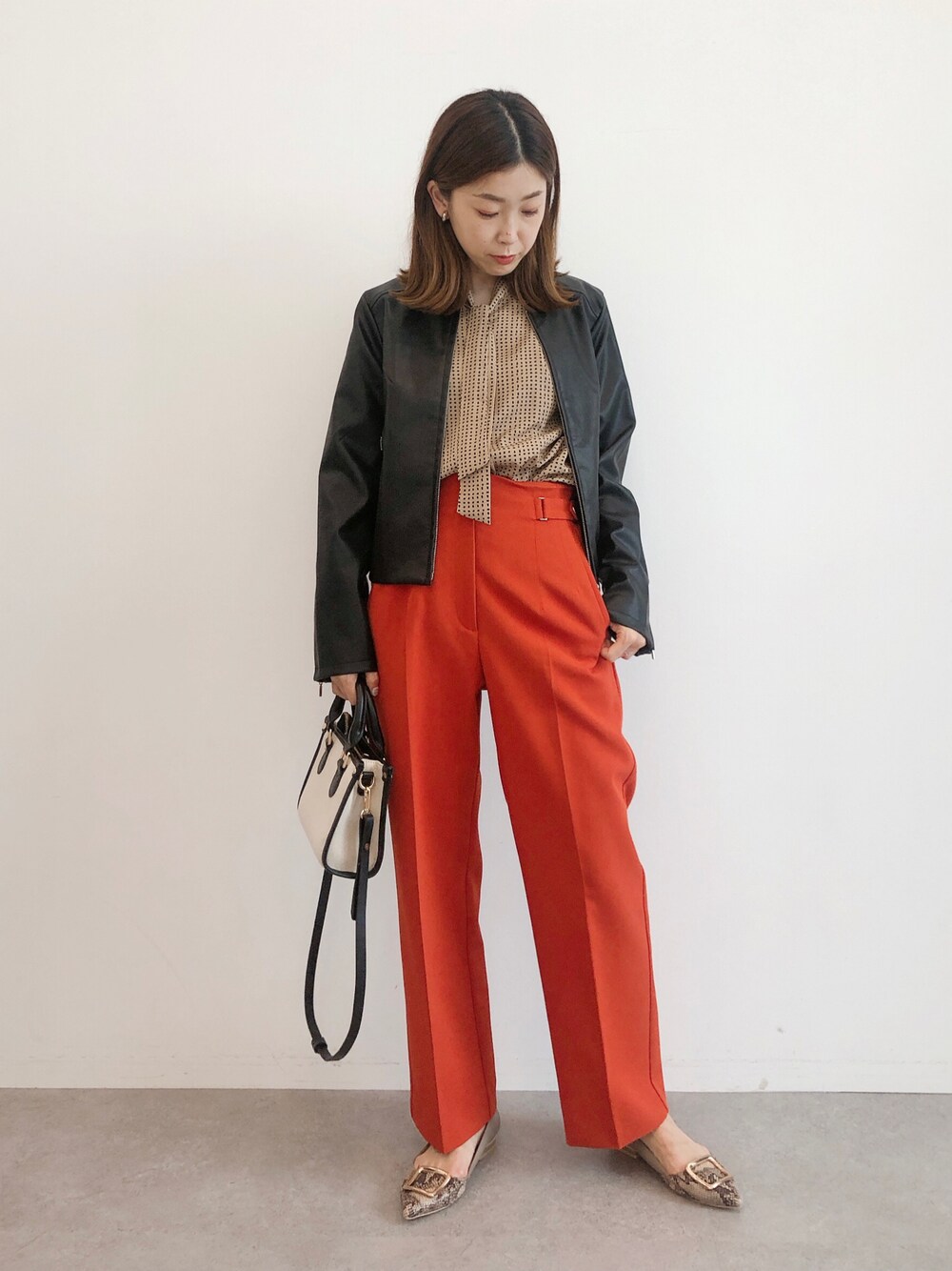 ブラック系のライダースジャケット、ベージュ系のシャツ/ブラウス、オレンジ系のその他パンツを着用したレディースの秋コーディネートの1枚目の写真