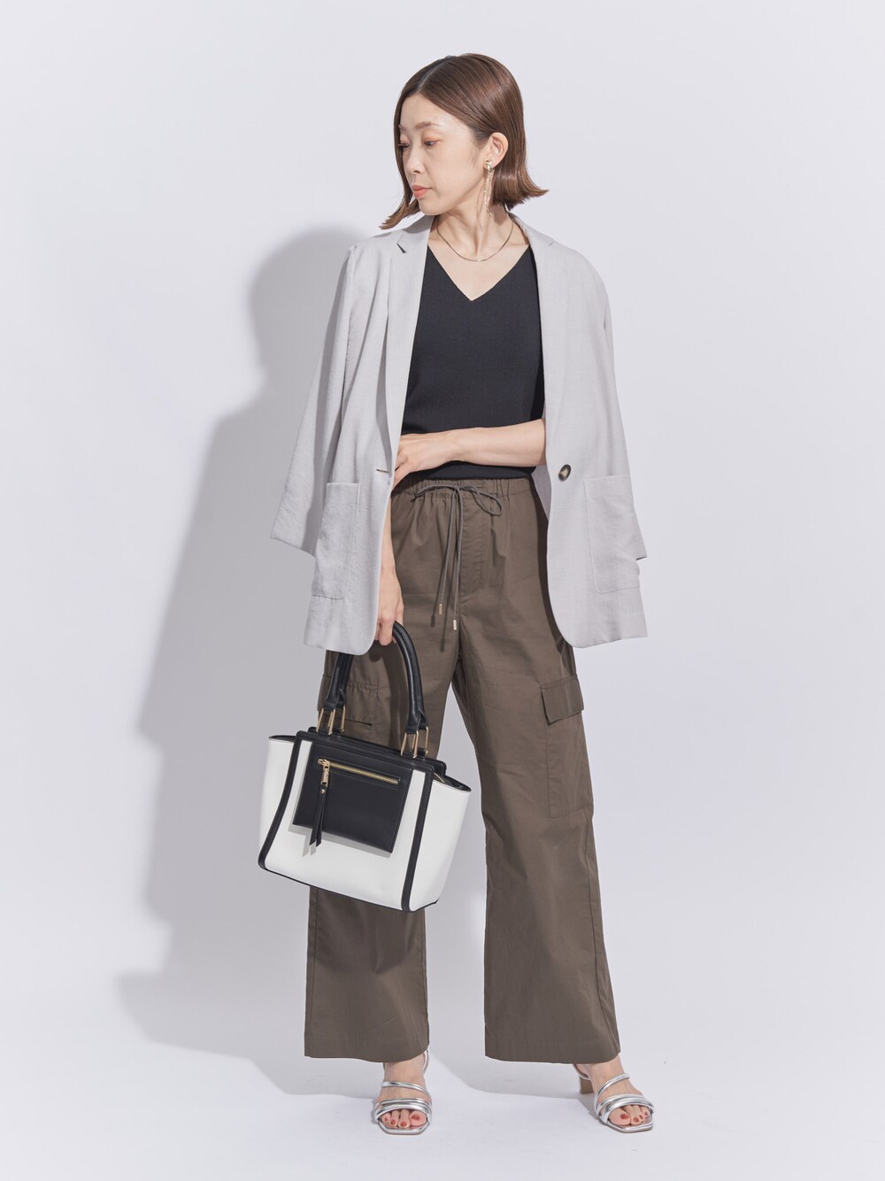 グレー系のテーラードジャケット、ブラック系のニット/セーター、グリーン系のカーゴパンツを着用したレディースの秋コーディネートの1枚目の写真