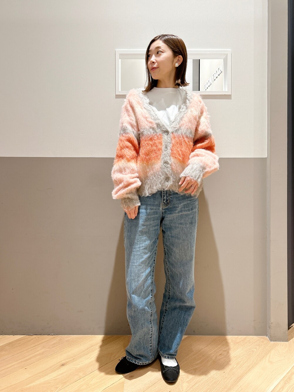 ピンク系のカーディガン/ボレロ、ホワイト系のTシャツ/カットソー、ブルー系のデニムパンツを着用したレディースの冬コーディネートの1枚目の写真