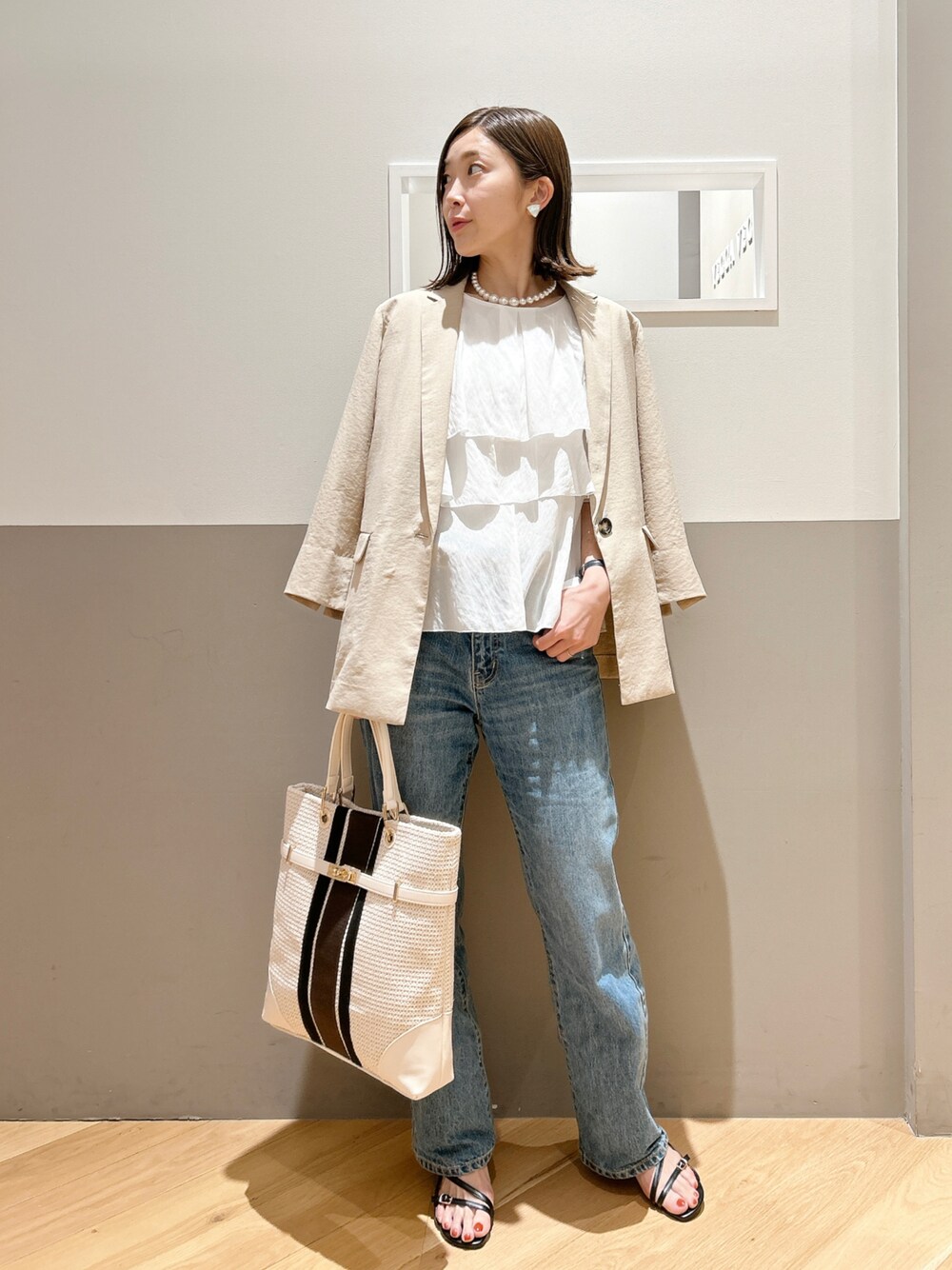 ベージュ系のその他アウター、ホワイト系のシャツ/ブラウス、ブルー系のデニムパンツを着用したレディースの春コーディネートの1枚目の写真