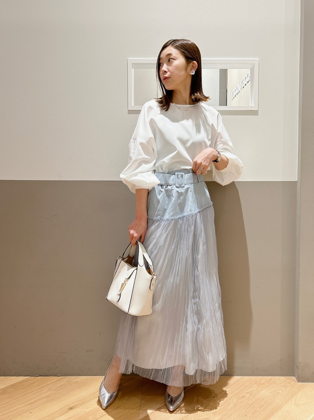 ホワイト系のシャツ/ブラウス、ブルー系のスカート、ホワイト系のエコバッグ/サブバッグを着用したレディースの冬コーディネートの1枚目の写真