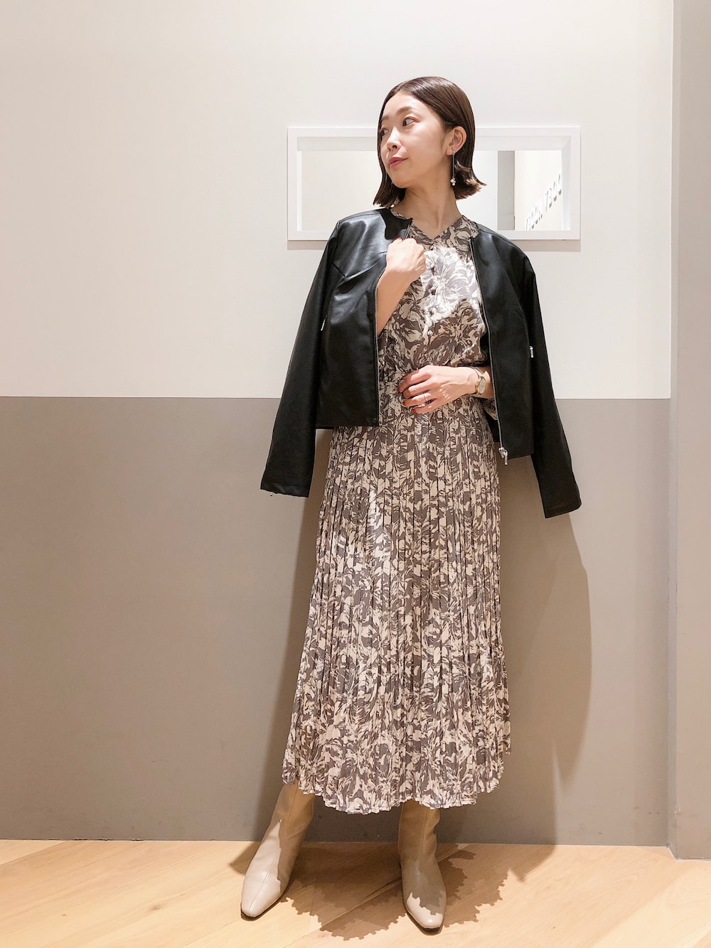 ブラック系のライダースジャケット、グレー系のワンピース、シルバー系のイヤリングを着用したレディースの秋コーディネートの1枚目の写真