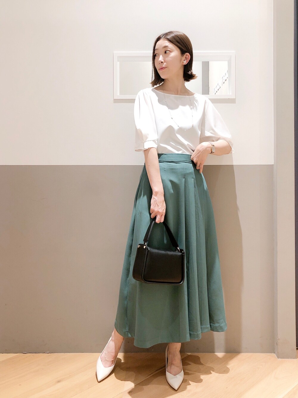 ホワイト系のシャツ/ブラウス、グリーン系のスカート、ブラック系のトートバッグを着用したレディースの夏コーディネートの1枚目の写真