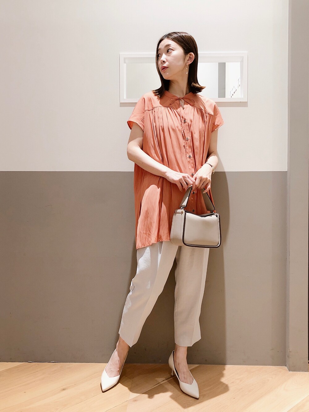 オレンジ系のシャツ/ブラウス、グレー系のその他パンツ、ベージュ系のトートバッグを着用したレディースの夏コーディネートの1枚目の写真
