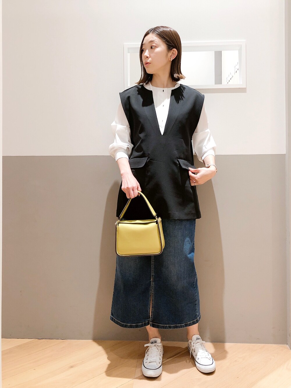 ブラック系のベスト、ホワイト系のシャツ/ブラウス、ブルー系のスカートを着用したレディースの春コーディネートの1枚目の写真