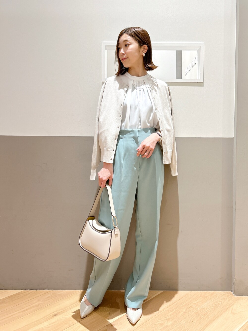 ベージュ系のカーディガン/ボレロ、ホワイト系のトップス、グリーン系のその他パンツを着用したレディースの春コーディネートの1枚目の写真