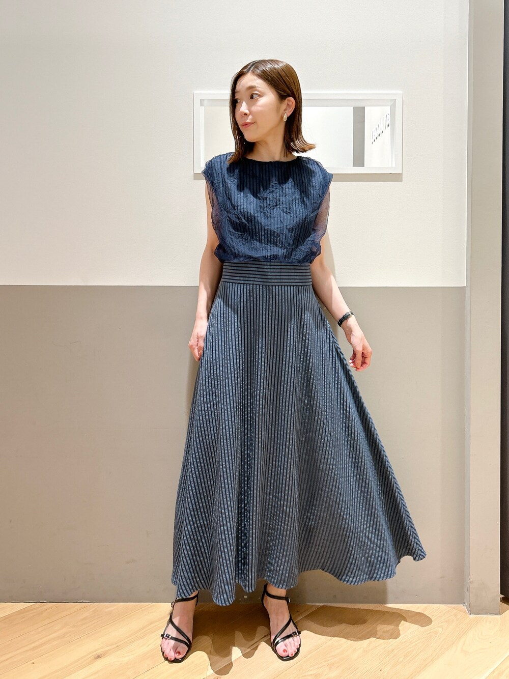 ブルー系のワンピース、ブラック系のサンダル、ゴールド系のイヤリングを着用したレディースの夏コーディネートの1枚目の写真