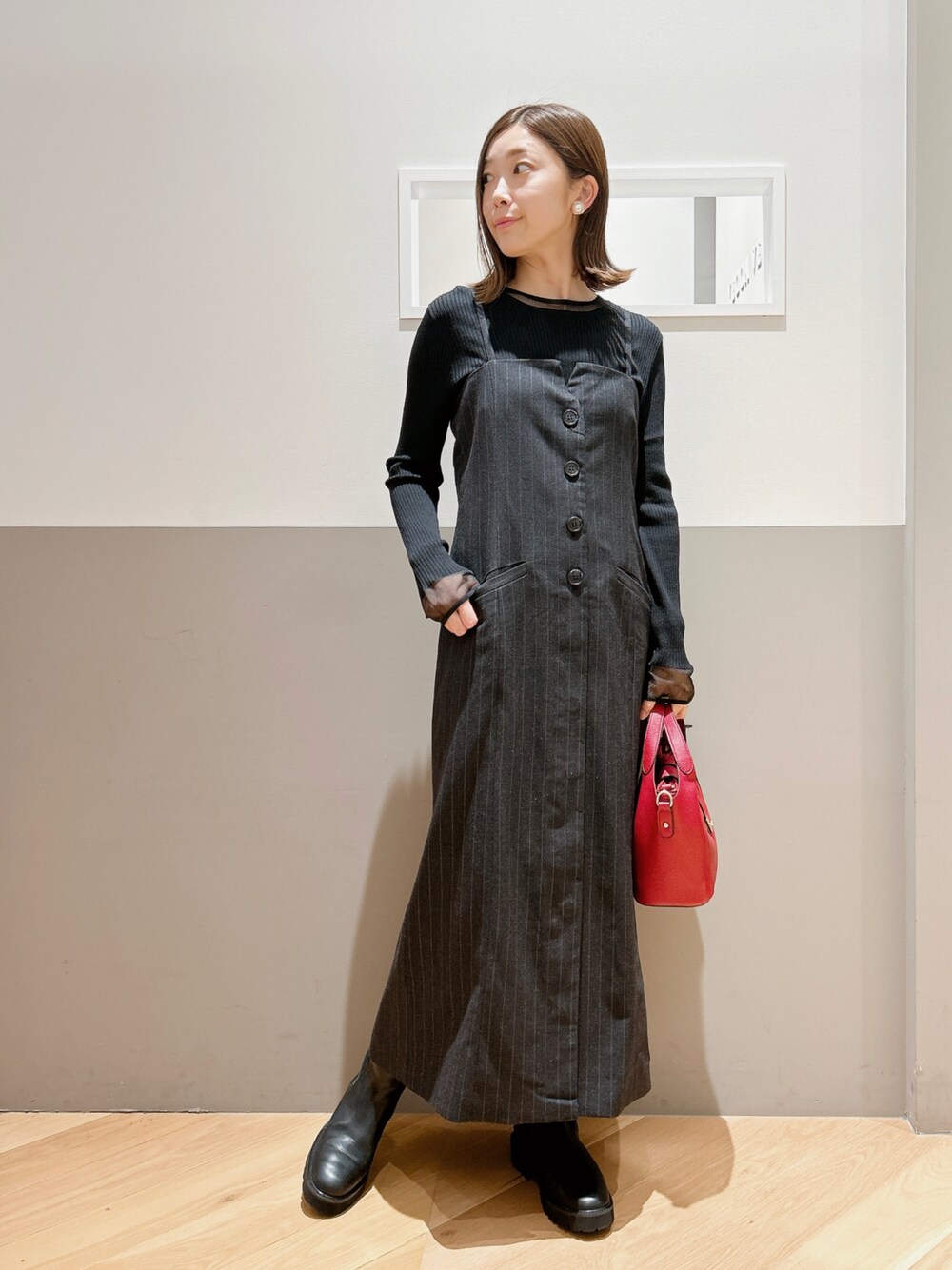 グレー系のワンピース、ブラック系のニット/セーター、ブラック系のシューズを着用したレディースの秋コーディネートの1枚目の写真