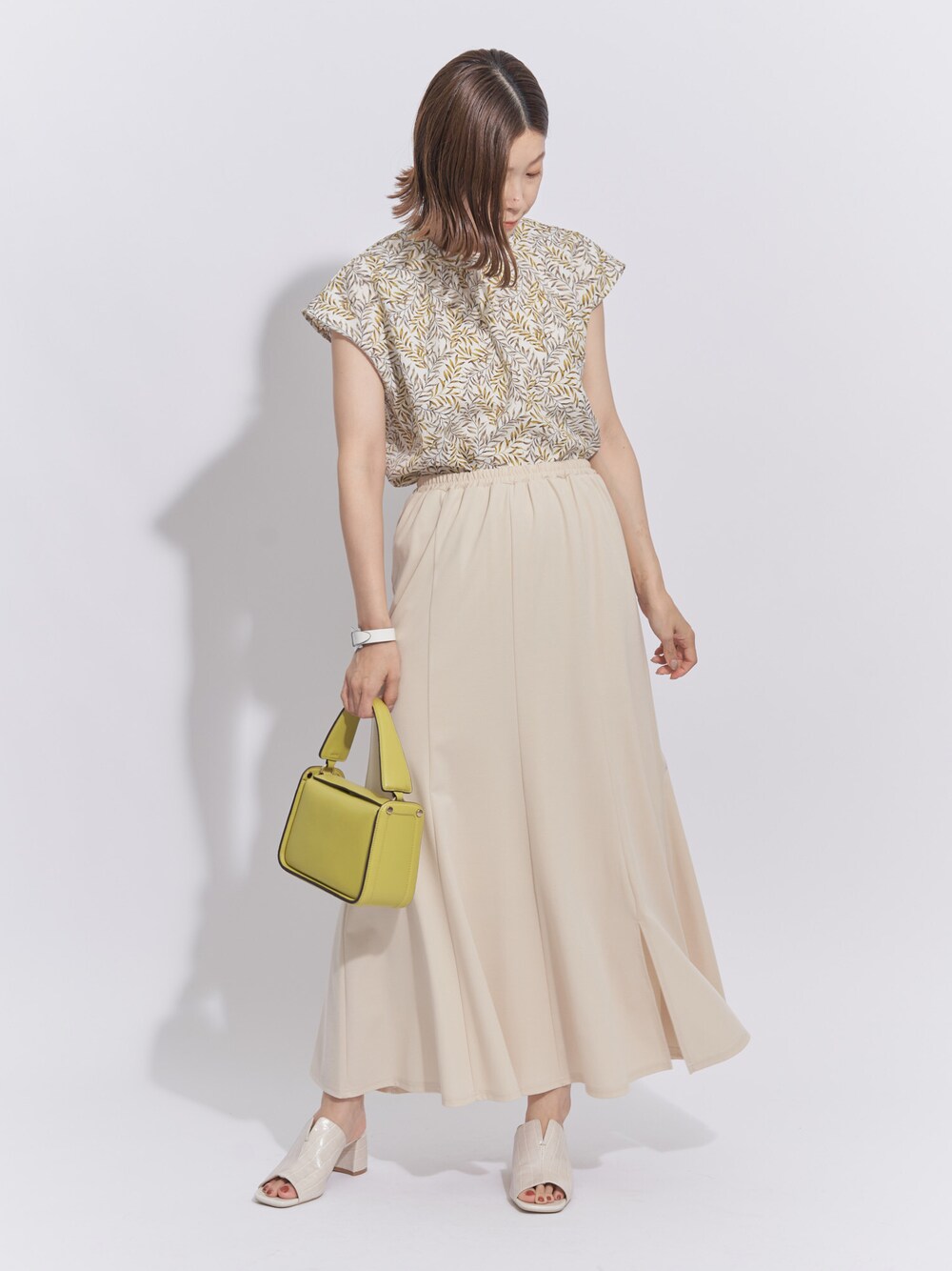 イエロー系のシャツ/ブラウス、ホワイト系のスカート、グリーン系のトートバッグを着用したレディースの秋コーディネートの1枚目の写真