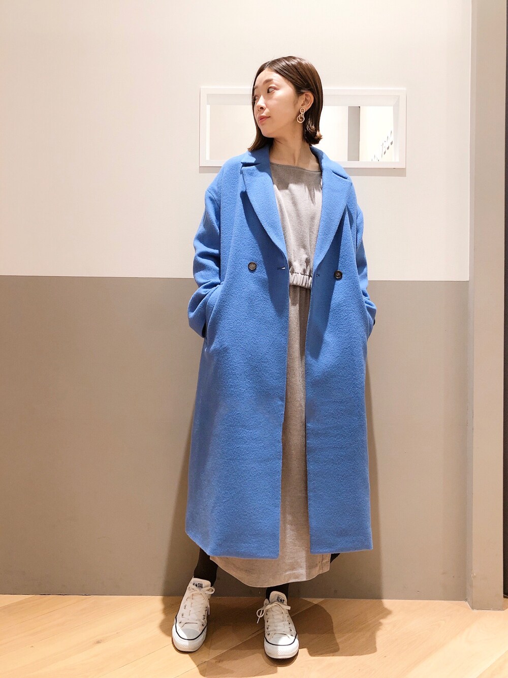 ブルー系のチェスターコート、グレー系のワンピース、ホワイト系のスニーカーを着用したレディースの冬コーディネートの1枚目の写真