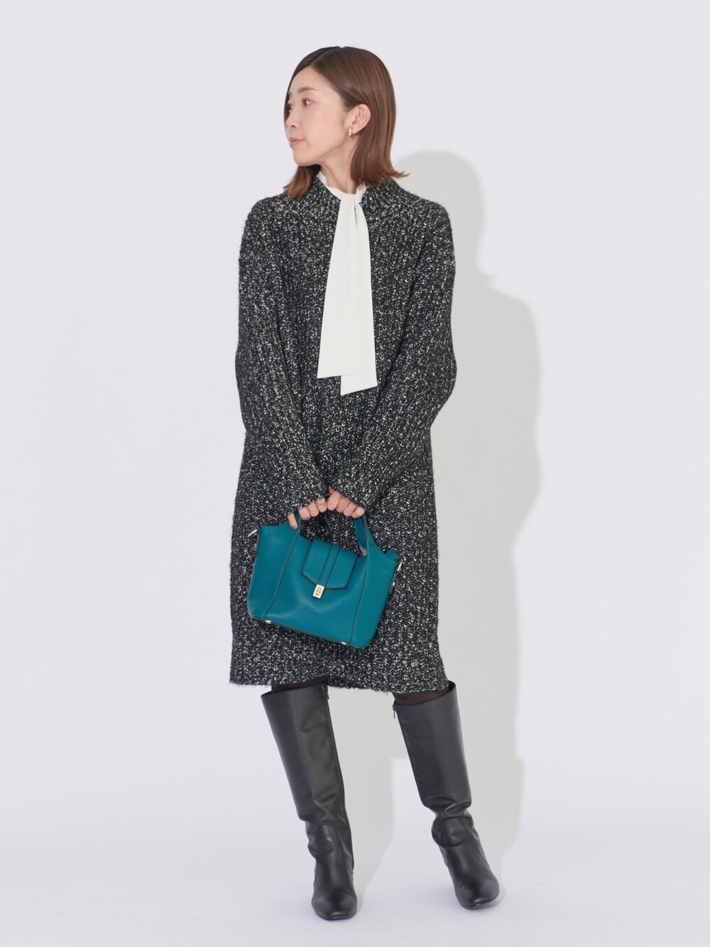 ブラック系のワンピース、ホワイト系のシャツ/ブラウス、グリーン系のハンドバッグを着用したレディースの冬コーディネートの1枚目の写真