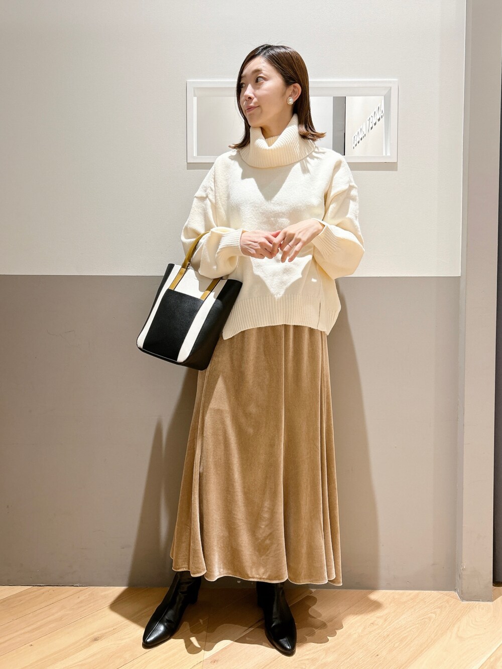ホワイト系のニット/セーター、ベージュ系のスカート、ブラック系のシューズを着用したレディースの冬コーディネートの1枚目の写真