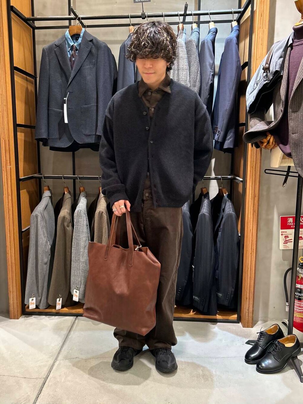 ブラウン系のトートバッグ、ブラウン系のその他アウター、ブラック系のカーディガン/ボレロを着用したメンズの秋コーディネートの1枚目の写真