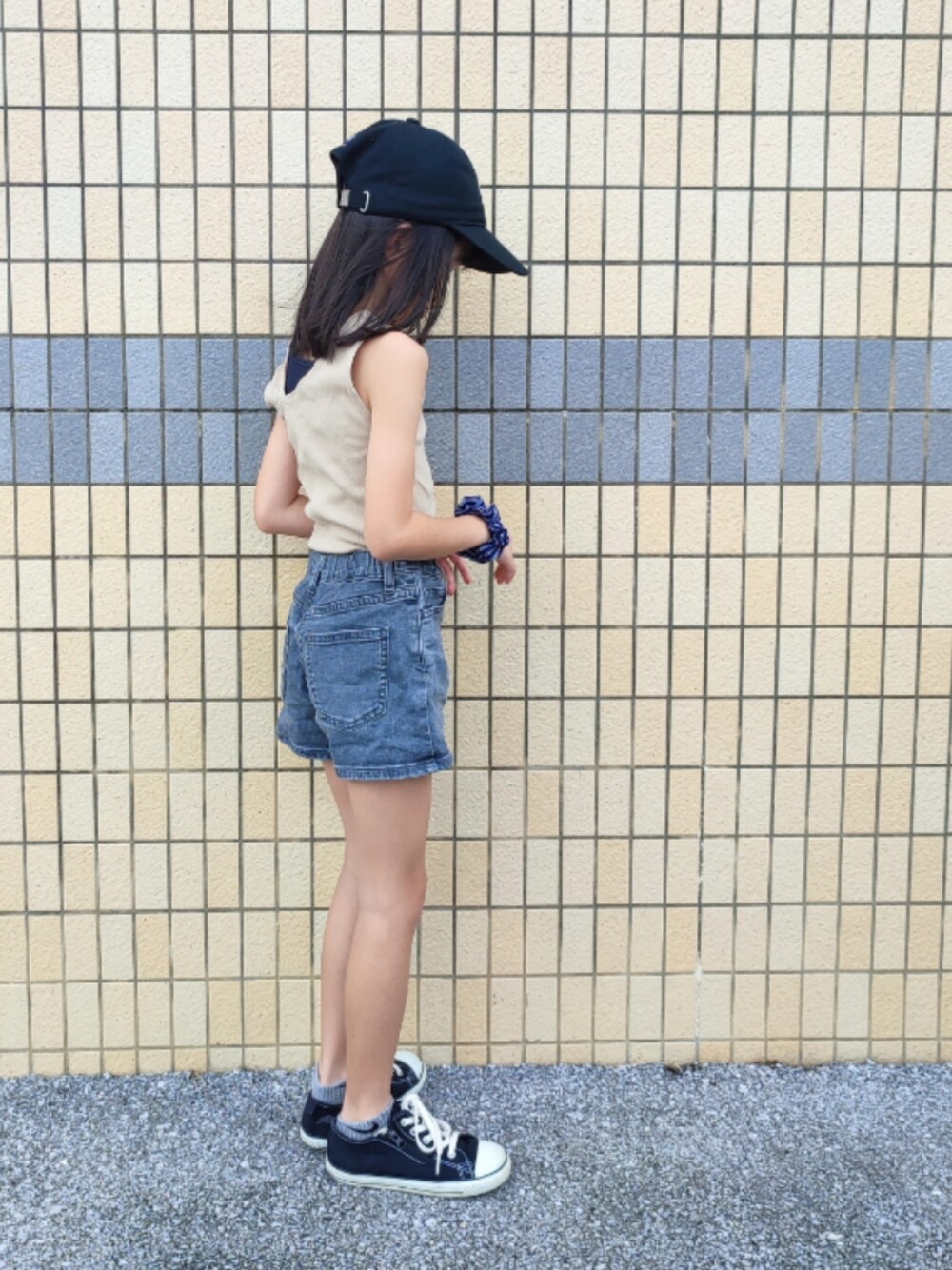 ベージュ系のタンクトップ、グレー系のデニムパンツ、ブラック系のスニーカーを着用したキッズの夏コーディネートの1枚目の写真