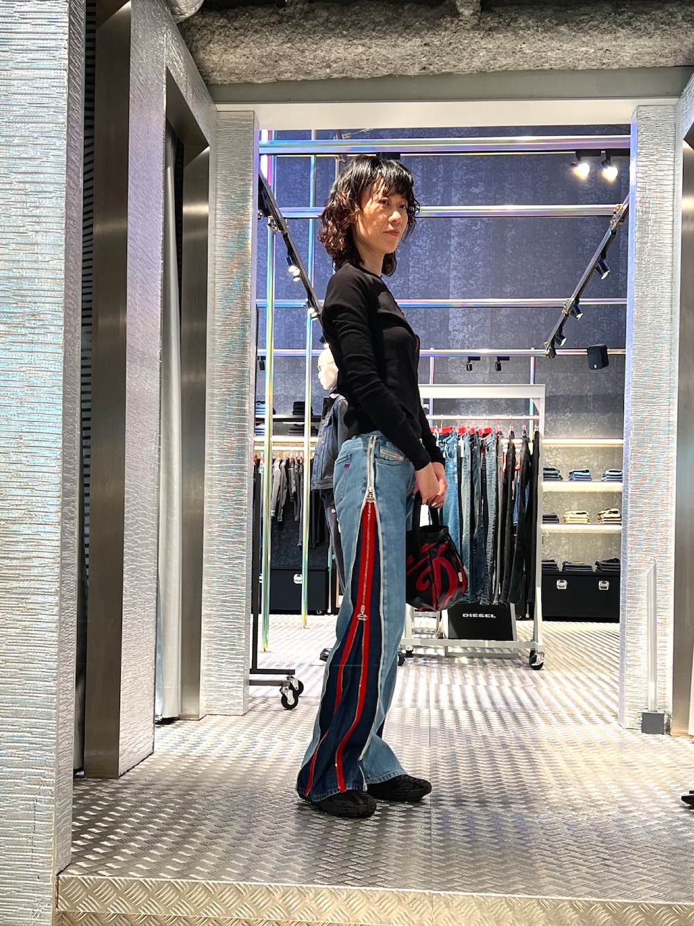 ブラック系のトップス、ブルー系のデニムパンツ、ブラック系のスニーカーを着用したレディースの冬コーディネートの1枚目の写真