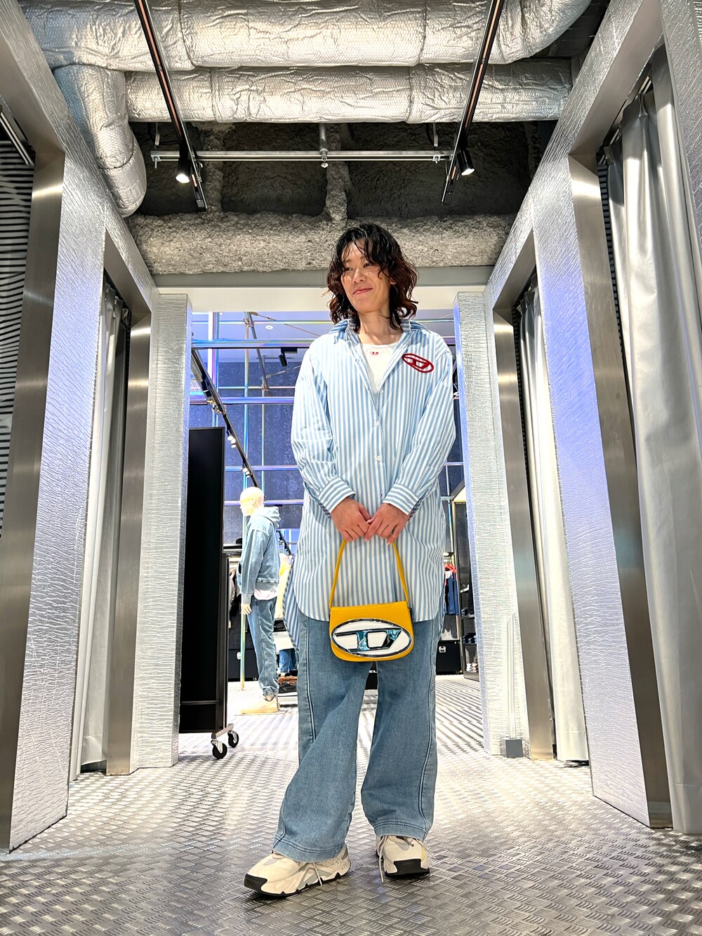 ブルー系のデニムパンツ、ホワイト系のシャツワンピース、イエロー系のショルダーバッグを着用したレディースの冬コーディネートの1枚目の写真