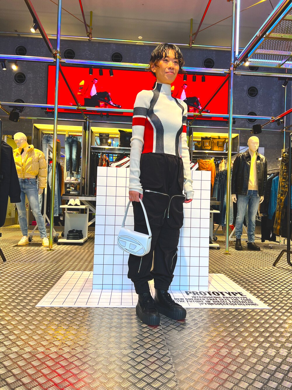 ホワイト系のニット/セーター、ブラック系のスニーカー、ホワイト系のショルダーバッグを着用したレディースの冬コーディネートの1枚目の写真