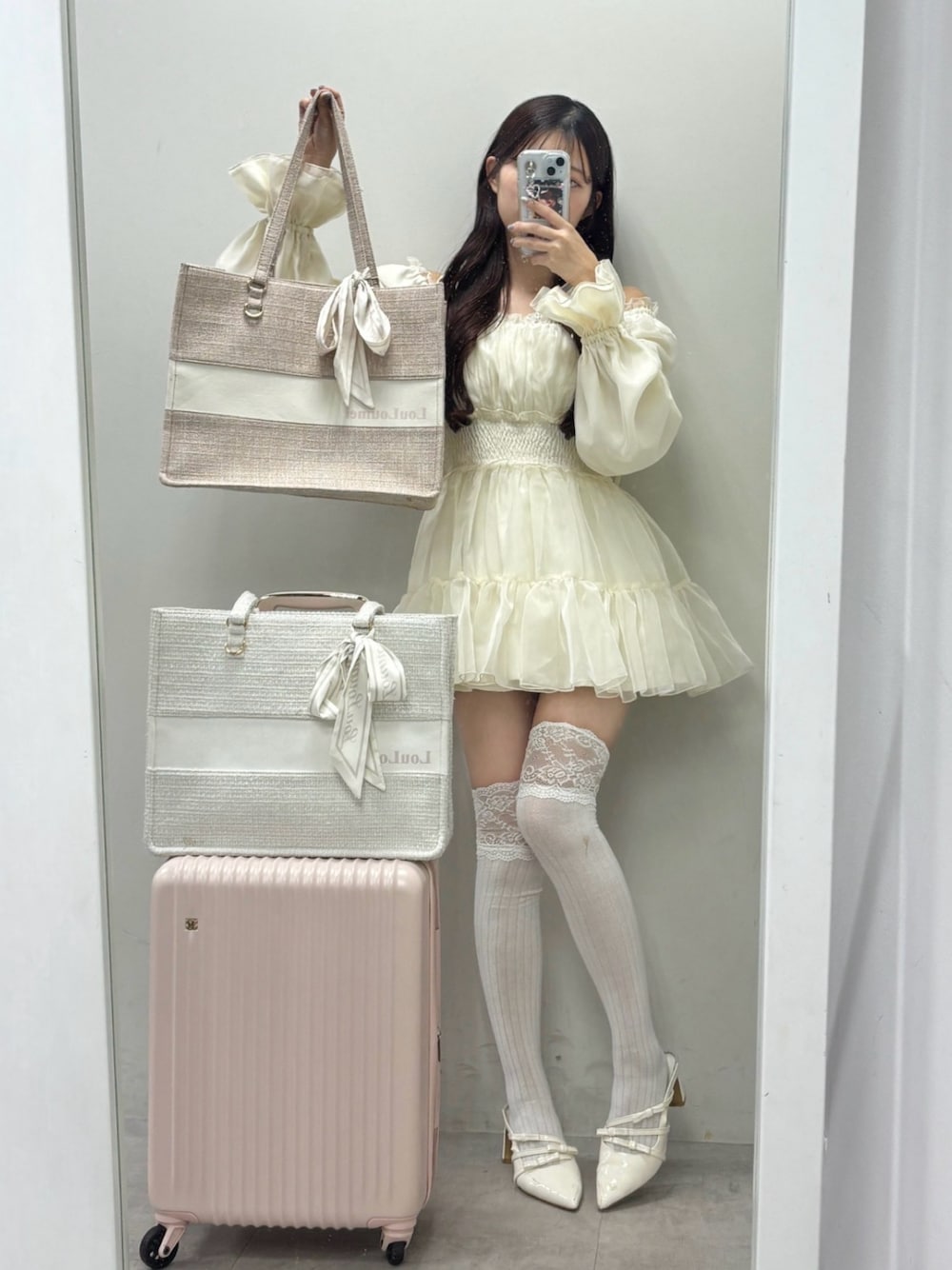 ホワイト系のトートバッグ、ピンク系のスーツケース/キャリーバッグ、ホワイト系のワンピースを着用したレディースの冬コーディネートの1枚目の写真