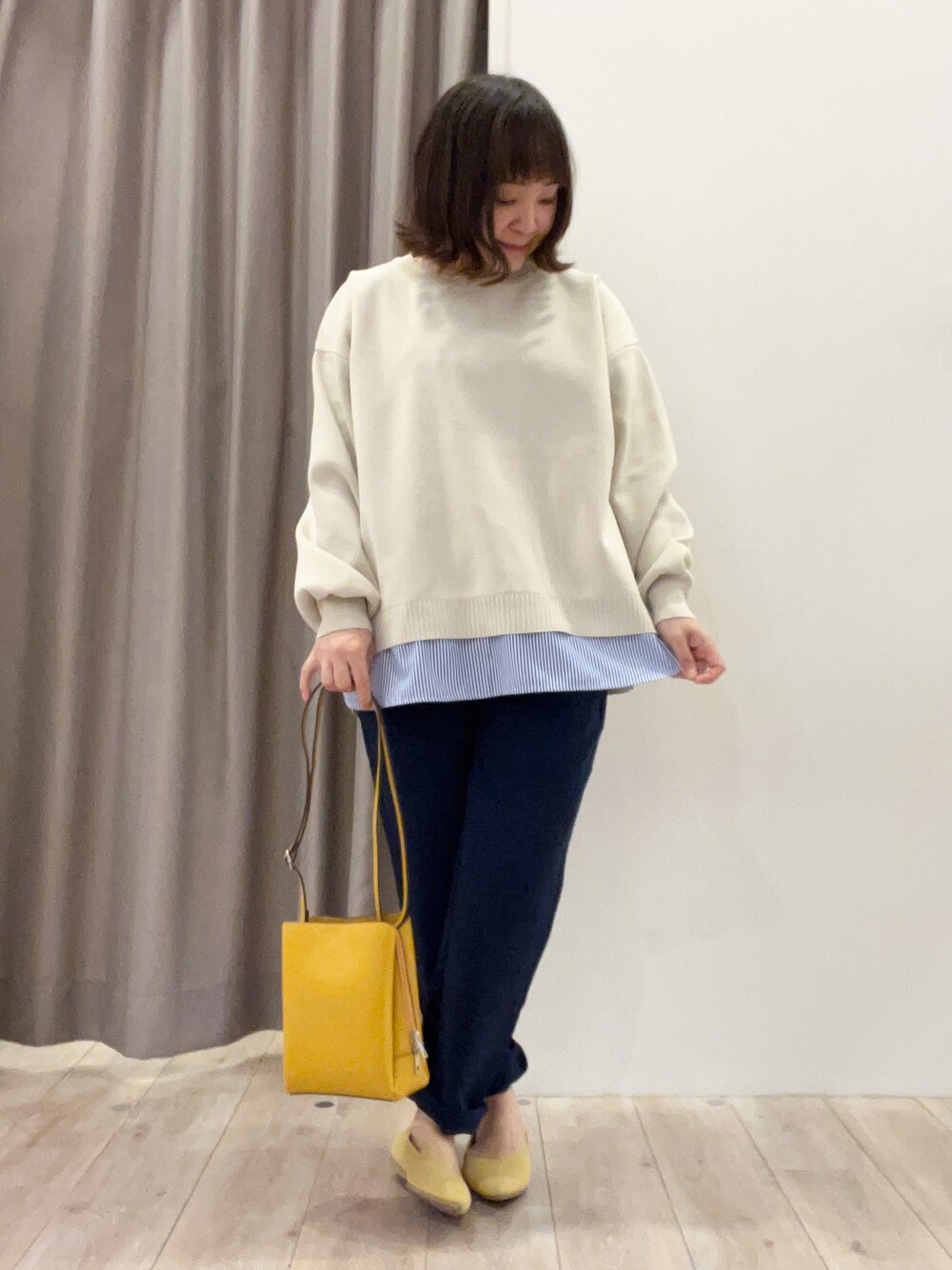 ベージュ系のニット/セーター、ブルー系のその他パンツ、イエロー系のショルダーバッグを着用したレディースの春コーディネートの1枚目の写真