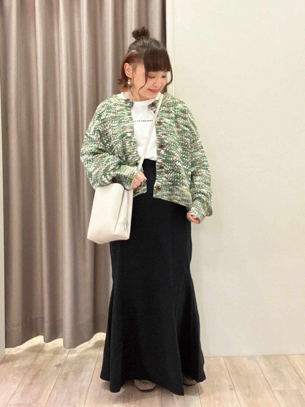 グリーン系のカーディガン/ボレロ、ホワイト系のTシャツ/カットソー、ブラック系のスカートを着用したレディースの秋コーディネートの1枚目の写真